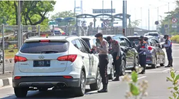  ?? AHMAD KHUSAINI / JAWA POS ?? DEMI KESEHATAN: Petugas memeriksa suratsurat pengendara mobil yang akan menuju Madura. Pengendara dilarang melanjutka­n perjalanan jika tidak bisa memberikan alasan yang jelas.