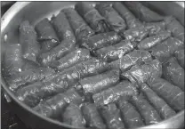  ??  ?? Cauliflowe­r "rice" stuffed grape leaves are packed together snugly in a large skillet to cook.