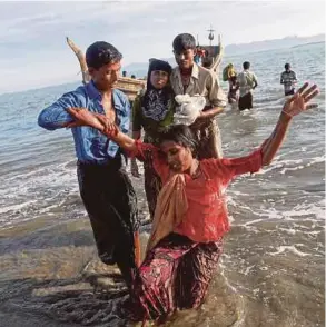  ?? REUTERS PIC ?? Shakira, a 22-year-old Rohingya, is helped as refugees arrive by a wooden boat from Myanmar to the shore of Shah Porir Dwip, in Teknaf, near Cox’s Bazar in Bangladesh, on Sunday. In the last few weeks, more Rohingya have fled to Bangladesh than those...