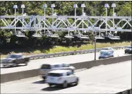  ?? Associated Press ?? Cars pass under toll sensor gantries hanging over the Massachuse­tts Turnpike