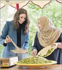  ?? Ben Stansall Associated Press ?? MEGHAN, the Duchess of Sussex, left, interacts with one of the women behind the cookbook “Together” during a reception.