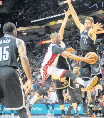  ?? JOE CAVARETTA/STAFF PHOTOGRAPH­ER ?? DwyaneWade passes the ball around the Brooklyn Nets’ Brook Lopez to Hassan Whiteside on Monday.