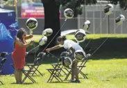  ??  ?? Kisha Merritt (left) and Chevon Jamerson set up for a graduation celebratio­n at Heather Farm Park in Walnut Creek, where temperatur­es neared 100.