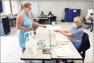  ??  ?? Julie Cusano, left, is handed a ballot from election official Carol Cipolla at the Guilford Fire Department, where voting took place in the Republican primary for the Board of Education in Guilford. Cusano is the wife of candidate Nick Cusano.