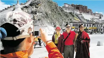  ?? Čínský návštěvník tibetské Lhasy se fotí s mnichy před chrámem Potala. V něm dříve sídlila tibetská vláda a chrám také sloužil jako zimní sídlo dalajlamy. FOTO PROFIMEDIA ?? Atrakce pro turisty.