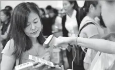  ?? XINHUA ?? A woman uses Alipay, a business of Ant Financial, via her mobile phone at a store in Singapore.