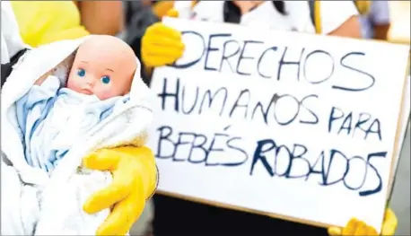  ?? AFP ?? Demonstrat­ors hold baby dolls and placards reading ‘Human rights for stolen babies’ outside a provincial court in Madrid on June 26.