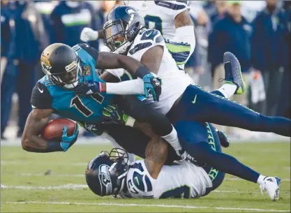  ?? The Associated Press ?? Jacksonvil­le Jaguars wide receiver Marqise Lee (11) is tackled by Seattle Seahawks cornerback Shaquill Griffin, top right, and safety Earl Thomas, bottom, after a reception during first-half NFL action on Sunday in Jacksonvil­le, Fla. The Seahawks lost...