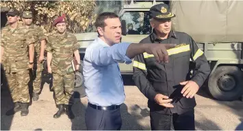  ?? — Reuters file photo ?? Greek Prime Minister Alexis Tsipras speaks with a firefighte­r officer as he visits the village of Mati, following a wildfire near Athens.