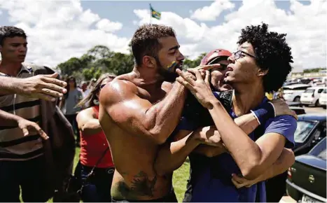  ?? (RICARDO MORAES/REUTERS) ?? Un manifestan­t anti-gouverneme­nt et un partisan de Dilma Roussef en discussion musclée près du palais présidenti­el à Brasilia.