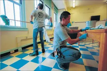  ?? Claire Hannah Collins Los Angeles Times ?? JORGE MUNOZ, left, and Eloy Avila wash windows and scrub desks at 49th Street Elementary. L.A. schools are expected to be spick-and-span, despite smaller cleaning crews, tighter budgets and a lot of wear and tear.