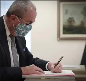  ?? EDWIN J. TORRES - THE ASSOCIATED PRESS ?? This photo provided by the New Jersey Governor’s Office shows Gov. Phil Murphy as he signs into law legislatio­n to set up a recreation­al marijuana marketplac­e, Monday, Feb. 22, 2021, in Trenton, N.J.