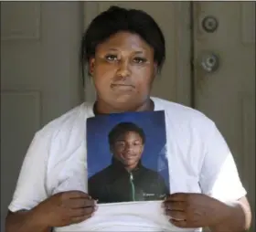  ?? TAE-GYUN KIM — THE ASSOCIATED PRESS ?? Monique Causey holds a portrait of her 14-year-old Malik, who was shot near her home in Chicago.