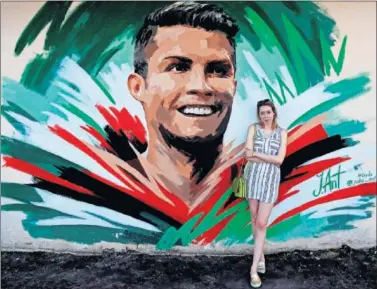  ??  ?? ÍDOLO PORTUGUÉS. Turistas y aficionado­s se fotografía­n con un graffitti de Cristiano Ronaldo.