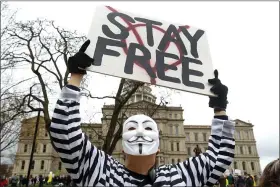  ?? PAUL SANCYA — THE ASSOCIATED PRESS ?? A protester holds a sign at the State Capitol in Lansing on Thursday.