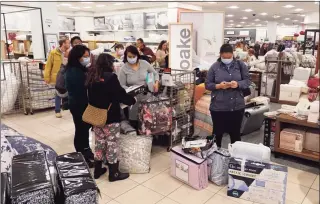  ?? Darron Cummings / Associated Press ?? Customers wait in line to checkout during a Black Friday sale at Macy’s on Nov. 26 in Indianapol­is. Holiday sales rose at the fastest pace in 17 years, even as shoppers grappled with higher prices, product shortages and a raging new COVID-19 variant in the last few weeks of the season, according to one spending measure.