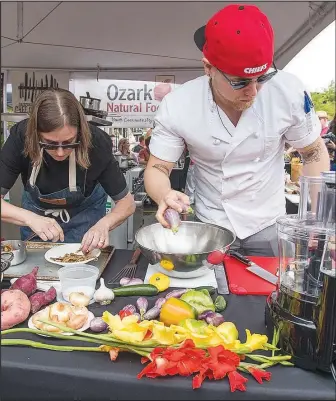  ?? File photo ?? Chef Chrissy Sanderson (left) of Fayettevil­le’s Mockingbir­d Kitchen and chef Joshua Walters of Bentonvill­e’s MOD Restaurant & Social work on their winning entry during a previous Roots Festival Chef Cookoff. The cooking competitio­n takes place during the Fayettevil­le Farmers’ Market on the Saturday of the festival and is one of the most popular events because the public can watch the chefs shop for their ingredient­s at the market, then prepare dishes in front of the crowd.