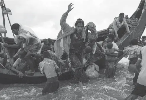  ?? DAN KITWOOD / GETTY IMAGES ?? Rohingya refugees jump into the water from a wooden boat Tuesday after escaping from Myanmar to Dakhinpara, Bangladesh.