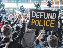  ?? John Minchillo The Associated Press ?? A protester holds a “Defund Police” sign during an Oct. 14 rally outside Barclays Center in New York. Several new state laws set to take effect address police brutality.