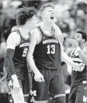  ?? Andy Lyons Getty Images ?? MOE WAGNER, right, celebrates with Michigan teammate D.J. Wilson after a basket.