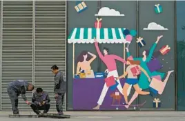  ?? ANDY WONG/AP ?? Workers check on cables Thursday near a display depicting shoppers outside a shopping mall in Beijing. China’s exports rebounded unexpected­ly in March.