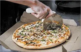  ?? SEAN PROCTOR/BLOOMBERG NEWS ?? Pizza companies have aggressive­ly advertised cheap deals to attract more diners.