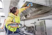  ??  ?? A constructi­on worker Maria Hernandez puts a polish on a stove hood above new ovens in Hilton Garden Inn’s new kitchen.