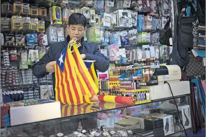  ?? [EMILIO MORENATTI/THE ASSOCIATED PRESS] ?? A vendor organizes esteladas, or independen­ce flags, to sell in a shop in Barcelona, Spain, on Wednesday. The Spanish Cabinet met in Madrid to determine how to respond to indication­s from Catalonia’s leader that the region will break away.