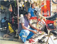  ??  ?? „Es gibt nicht viel Arbeit hier“, sagt der Mechaniker Artur Carlos (links), hinter ihm seine Werkstatt mit nicht einmal zehn Quadratmet­ern. Mosambik gehört zu den ärmsten Ländern der Welt.