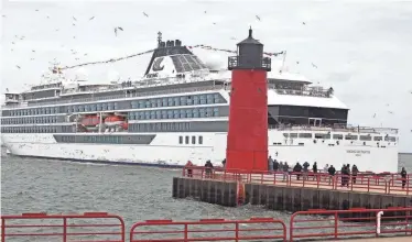  ?? CHELSEY LEWIS/MILWAUKEE JOURNAL SENTINEL ?? A crowd watches as the Viking Octantis passes the Pierhead Light in Milwaukee on its way to dock at the Port of Milwaukee on Friday, May 6. The Octantis is the biggest ship to sail the Great Lakes, and it’s the first Viking ship to sail the lakes and dock in Milwaukee.