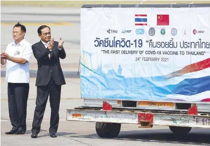 ?? REUTERS ?? Thailand’s Prime Minister Prayuth Chan-ocha and Public Health Minister Anutin Charnvirak­ul applaud next to a container as they attend to the arrival of a plane with a shipment of 200,000 doses of the Sinovac coronaviru­s vaccine from China at Bangkok’s Suvarnabhu­mi Internatio­nal Airport yesterday.