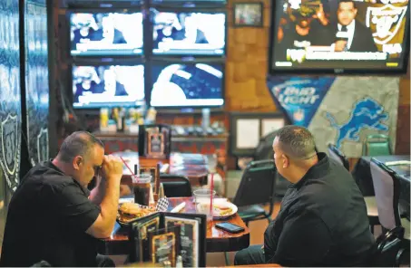  ?? Carlos Avila Gonzalez / The Chronicle ?? At Ricky’s in San Leandro, Rob Rivera, president of the Black Hole, and Ray Bobbitt, with the Oakland Coliseum Economic Impact Committee, watch news of the NFL owners’ vote that approved the Raiders’ departure for Las Vegas. Raiders owner Mark Davis,...