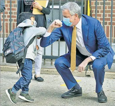  ??  ?? PUT ’ER THERE, PAL: Mayor de Blasio elbow bumps with Oliver, 4, at the Mosaic Pre-K Center in Queens, while anxious parents peek in on their PS 20 preschoole­rs in Brooklyn as city schools reopened on Monday.