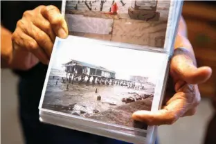  ?? Houston Chronicle via AP ?? Lalo Ojeda holds a photo on May 22 that he took of the seawall after Hurricane Ike in Galveston, Texas.