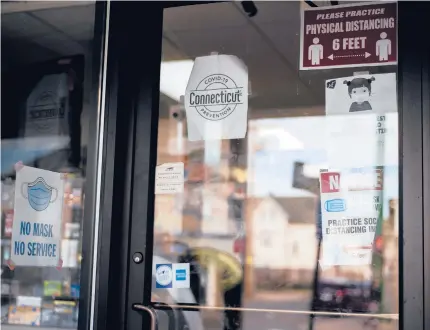  ?? KASSIJACKS­ON/HARTFORD COURANT ?? Signs for mask-wearing are posted on the front door of Aden Corner Store off of Grand Avenue in New Haven on Friday.