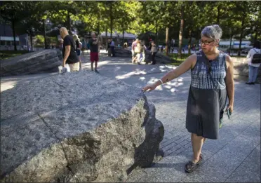  ?? MARY ALTAFFER—ASSOCIATED PRESS ?? In this Thursday, Aug. 29, 2019, photo a visitor touches one of the granite slabs at the 9/11Memorial Glade at the National September 11Memorial & Museum in New York. When the names of nearly 3,000Sept. 11 victims are read aloud Wednesday, Sept. 11at the World Trade Center, a half-dozen stacks of stone will quietly salute an untold number of people who aren’t on the list. The granite slabs were installed on the memorial plaza this spring. They recognize an initially unseen toll of the 2001 terrorist attacks: firefighte­rs, police and others who died or fell ill after exposure to toxins unleashed in the wreckage.