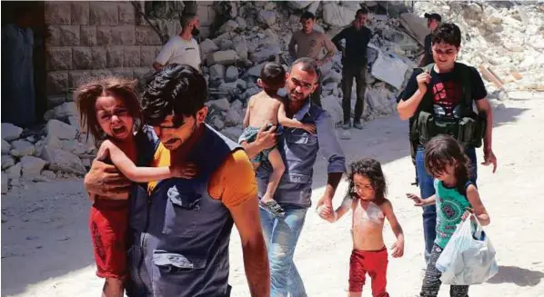  ??  ?? Men carry injured children amid the rubble of destroyed buildings following air strikes on the rebel-held neighbourh­ood of Al Mashhad in Aleppo. The Syrian regime is offering to open four routes for civilians and fighters to leave the city.