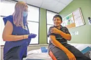  ?? STAFF PHOTO BY TROY STOLT ?? Joel Pedro, 13, looks at Nurse Practition­er Meghan Whitehead before receiving a dose of the COVID-19 vaccine at LifeSpring Community Health on Wednesday in Chattanoog­a.