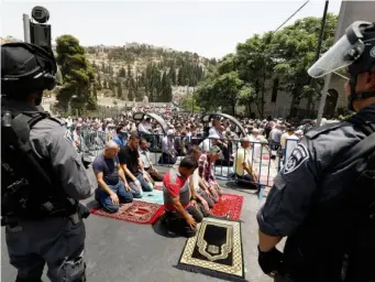  ??  ?? Palestinia­ns pray on the street close to Lion's Gate in the Old City of Jerusalem, closely watched by Israeli security during a mass street Friday prayer on 21 July 2017. (EPA)