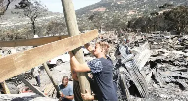  ?? PICTURE: EPA ?? HELPING HANDS: Volunteers help residents rebuild after a fire in Imizamo Yethu in Hout Bay on March 14. Over 15 000 residents were affected, with about 4 500 shacks gutted by the blaze, in which at least four people died.