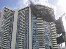  ?? Audrey McAvoy / Associated Press ?? Smoke rises after a fire started on the 26th floor of a Honolulu apartment building. Some residents were reported trapped.