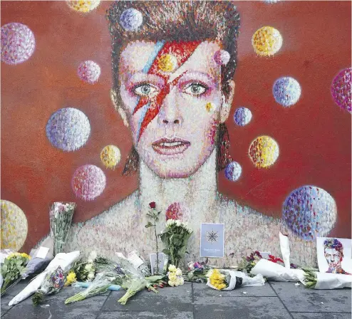  ?? CARL COURT / GETTY IMAGES ?? Flowers are laid beneath a mural of David Bowie in London, England, on Monday.