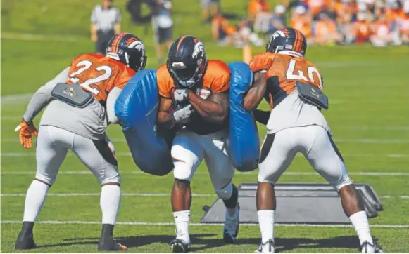  ?? Andy Cross, The Denver Post ?? Broncos rookie De’Angelo Henderson squeezes through the pads held by teammates C.J. Anderson, left, and Juwan Thompson during training camp Wednesday. Henderson, a sixth-round pick, broke Coastal Carolina records in carries, rushing yards, rushing...