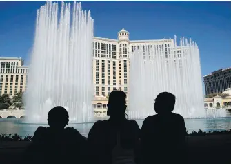  ??  ?? People watch the fountains dance at the reopening of the Bellagio hotel and casino on Thursday in Las Vegas. All casinos in Nevada were allowed to reopen this week after a nearly three-month closure due to the COVID-19 pandemic.