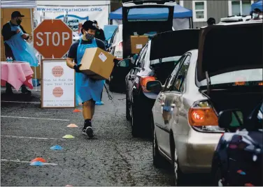  ?? DAI SUGANO — STAFF PHOTOGRAPH­ER ?? Hunger at Home volunteer Andrew Wilson, 18, carries a box of essential items to someone’s car trunk during a food giveaway in San Jose on Wednesday.