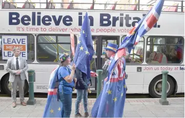  ??  ?? Anti-Brexit protestors carry EU flags as they stand alongside the pro-Brexit Leave Means Leave battle bus parked on the street prior to an event on the sidelines of the Conservati­ve Party Conference 2018, in Birmingham. — AFP photo