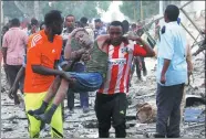  ?? FEISAL OMAR / REUTERS ?? Civilians assist a man, injured from a suicide car bomb explosion, at the gate of Naso Hablod Two Hotel in Hamarweyne district of Mogadishu, Somalia, on Saturday.