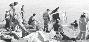  ??  ?? JATUH LAUT: Anggota bomba berusaha mengeluark­an kereta mangsa dari laut.