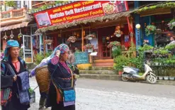  ??  ?? Hmong hilltribe women walking along a street as they sell tourist souvenirs in the northern Sapa tourist town.