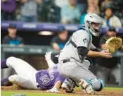  ?? DAVID ZALUBOWSKI/AP ?? Marlins catcher Jacob Stallings fields a throw as the Rockies’ Ezequiel Tovar scores on a double by Jurickson Profar in the seventh inning Monday in Denver.